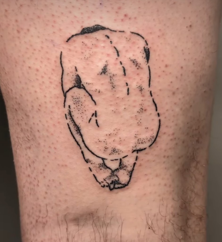 A tattoo above the knee, using black sketch like lines for the outline and dotwork to show shading. The design is of a naked figure in the foetal position with its back to the viewer. The top of the head is only just visible, and the feet cross over each other where the figure is sitting on them